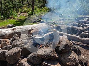 Camping lunch is cooked on a campfire in pots, in a forest camp