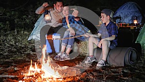 Camping, mum with son and daddy with kerosene lamp in hands photographed on gadget near fire, parents and kid