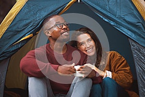 Camping, nature and couple embrace in tent with morning drink, happy vacation or romantic date. Relax, man and woman