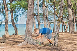 Camping people outdoor lifestyle tourists in summer forest near lazur sea. Blond serious boy in blue t-shirt study photo
