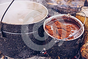 Camping pot on fire with coffee and hot water for tea or stew. Outdoor steaming food. Wildlife lifestyle cooking delicious meal,