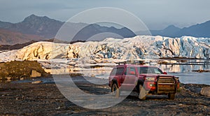 Camping rig pickup truck parked offroad in front of a glacial lake