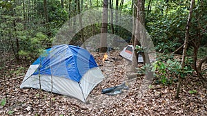 Camping tent in the Blue Ridge Mountains in Asheville, North Carolina. Outdoor lifestyle with axe, cast iron skillet, flannel blan