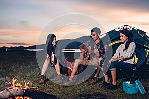 Camping tent camp in nature happy friends group night party bonfire and playing guitar together