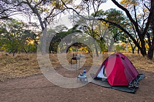 Camping with tent, chairs and camping gear at sunrise. Adventure traveling in South Africa National Park. Outdoor activities.