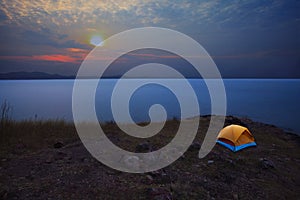 Camping tent in mountain with sun rising on sky