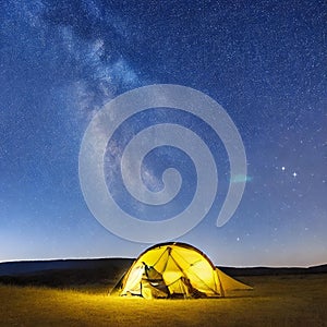 Camping tent in open field. Camp overnight. Camping tent with light on at night