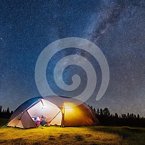 Camping tent in open field. Camp overnight. Camping tent with light on at night