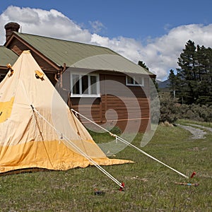 Camping tent and wooden hut in the mountains