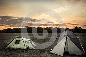 Camping tents on camping sites on summer flatland field plain and dramatic sunset sky during camping holidays