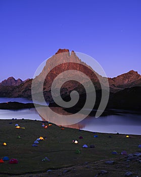 Camping tents on Lake Gentau at night with Mount Midi d`Ossau reflected on the lake