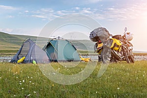 Camping tents and traveling motorcycle on flower meadows in the morning