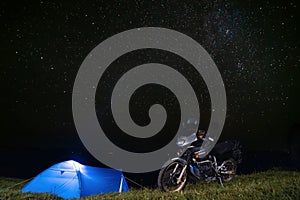 Camping on top of a mountain. The stars are shining. A tent and a touring motorcycle. Travel and extreme recreation. Ukraine. Copy