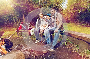 Happy family sitting on bench at camp fire