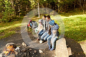 Happy family sitting on bench at camp fire