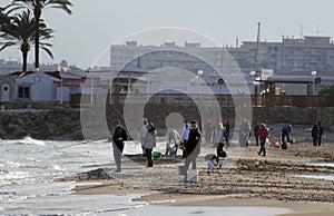Campoamor, Murcia, Spain, February 8, 2020: Group of fisherman fishing from the sea shore at sunset