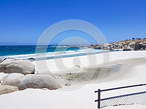 Camps Bay Beach behind fence and rocks, Cape Town