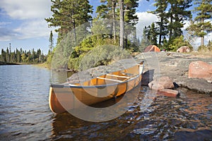 Campsite and canoe on rocky shore of lake