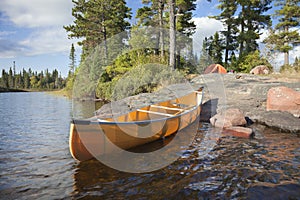 Campsite and canoe on rocky shore of lake photo