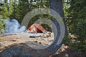 Campsite with orange tent and fire in the northern Minnesota wilderness