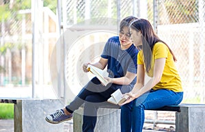 On a campus, a couple of students are studying together, and a teenager sits on a seat beside a sports court with a book