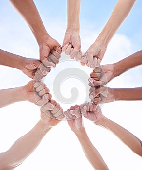 We can achieve it if we do it together. a group of unrecognizable people making a circle with their fists outside.