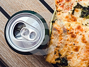 Can of beer and a piece of pizza. Top view