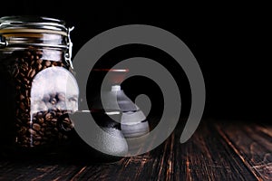 A can of coffee, a cup and a turk on a wooden table, on a black background