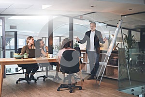 We can do this if we work together. a mature businessman delivering a presentation to his coworkers in the boardroom of