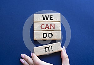 We can do it symbol. Concept words We can do it on wooden blocks. Beautiful deep blue background. Businessman hand. Business and