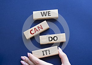 We can do it symbol. Concept words We can do it on wooden blocks. Beautiful deep blue background. Businessman hand. Business and