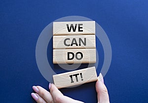 We can do it symbol. Concept words We can do it on wooden blocks. Beautiful deep blue background. Businessman hand. Business and