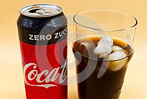 Can and glass of Coca Cola with ice and water droplets.
