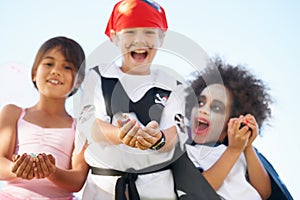 Can we have some more, please. Costumed children holding out their hands for candy at Halloween.