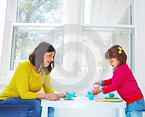 Can I pour you a cup of tea, Mom. an adorable little girl having a tea party with her mother at home.