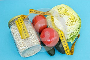 A can of oatmeal, tomatoes, cucumbers, cabbage and tape measure. The concept of proper nutrition to maintain beauty and health. We