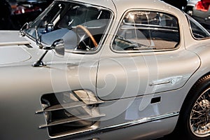 Can see what`s inside. Old silver shiny car standing indoor at vehicle exhibition