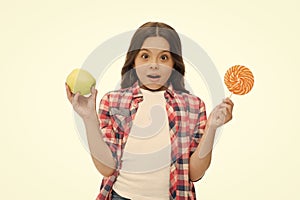 Can sugar sweet taste make us happy. Girl cute smiling face holds sweet lollipop and apple. School lunch alternatives