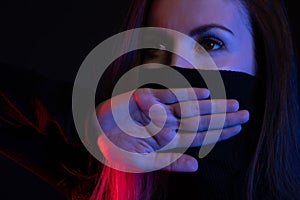 Can't Say Anything. Girl Close her Mouth with Crossed Palms on neon Background