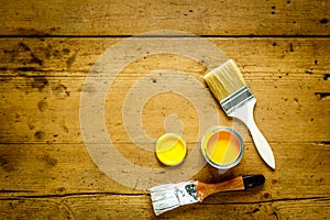 Can with yellow paint and brush on wooden background