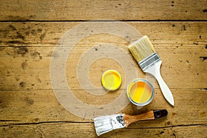 Can with yellow paint and brush on wooden background