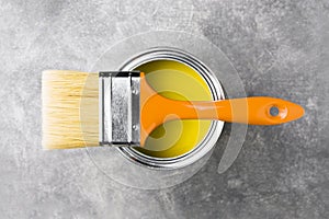 Can of yellow paint on gray background.