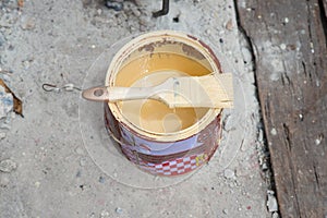 Can of yellow paint and professional brush on ground