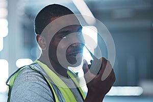 Can you bring the forklift please. a handsome young contractor standing alone in the warehouse and using a walkie talkie