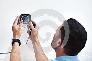 Can you guys see me down there. Shot of a mature man installing a security camera on a building.