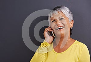 Can you hear me now. a mature woman talking on a mobile phone in a studio.