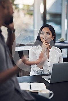 Can you please tone it down a bit. a young businesswoman gesturing for her colleague to be quiet in an office.