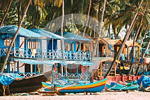 Canacona, Goa, India. Fishing Boat And Famous Painted Guest Houses On Palolem Beach Against Background Of Tall Palm