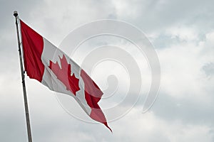 Canada flag with blue sky and clouds