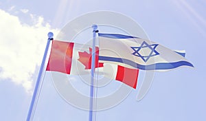 Canada and Israel, flags waving against blue sky